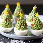 Turn classic deviled eggs into Christmas trees with avocado, herbs, and festive toppings. A fun and delicious holiday appetizer idea.